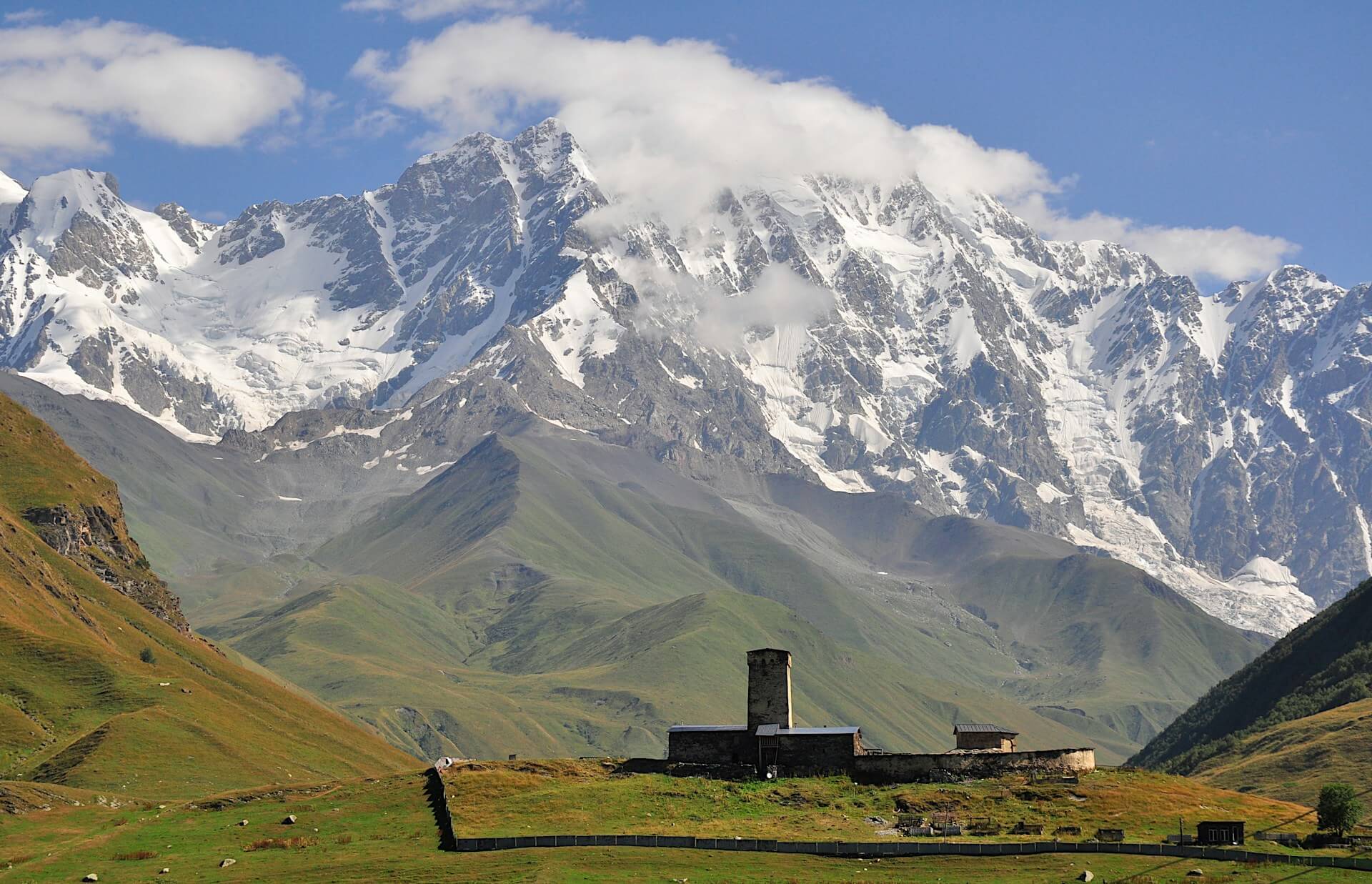 Snow-capped Caucasus peaks rising above a stone-tower Svaneti village