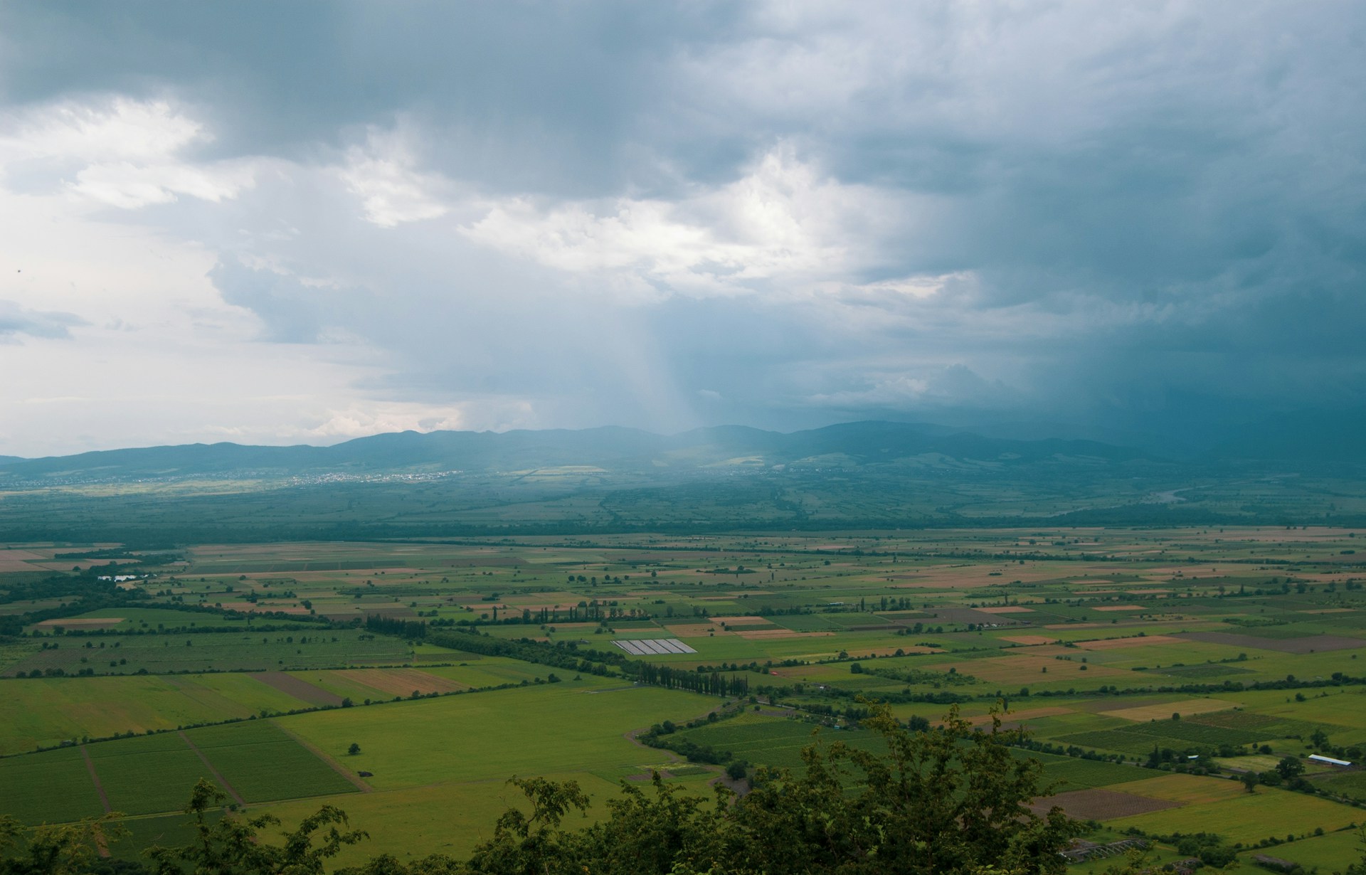Aerial view of patchwork farmland in the Alazani Valley beneath distant hills
