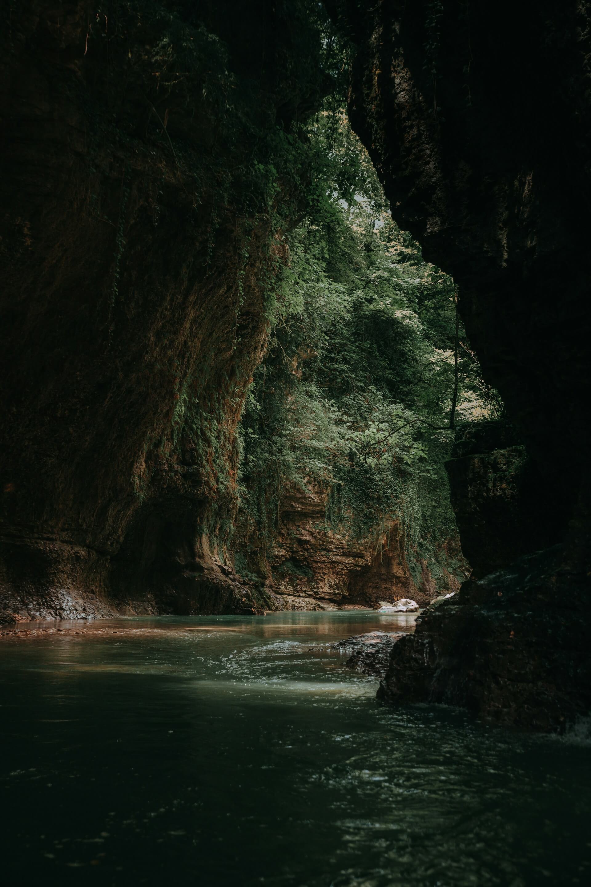 A narrow limestone canyon with moss-covered cliffs above a turquoise river